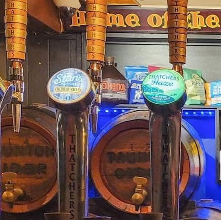 Cider taps in front of the old wooden barrels behind the bar