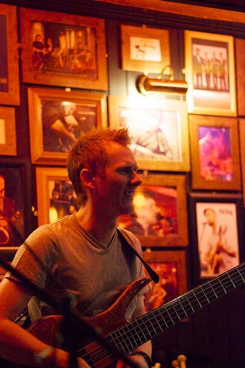 A guitarist playing under the warm lights of the Cori